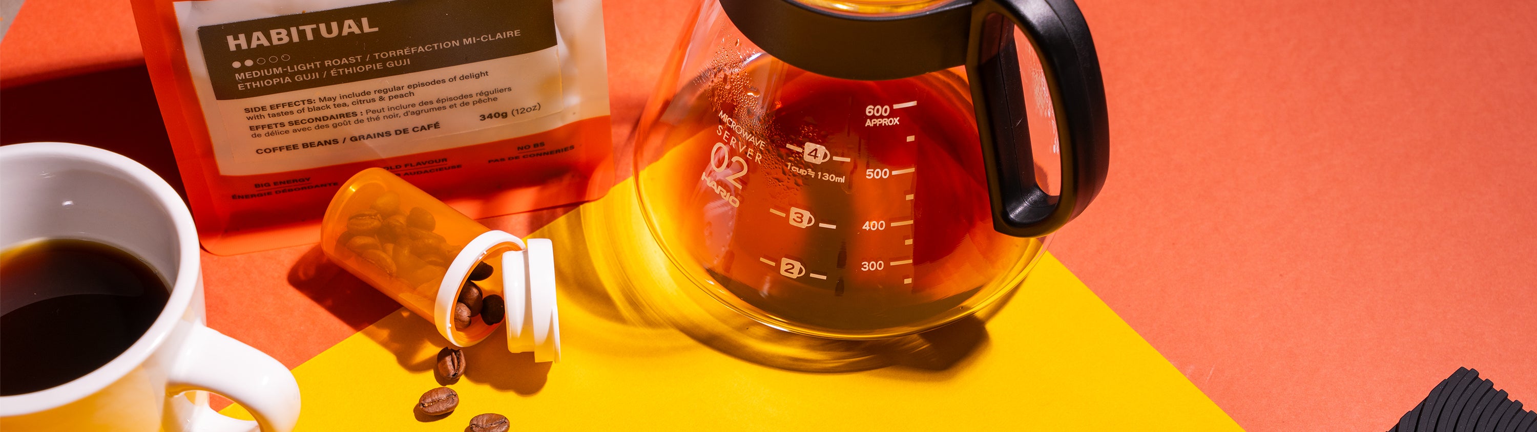 Coffee cup, coffee beans, and a glass carafe on a colorful background